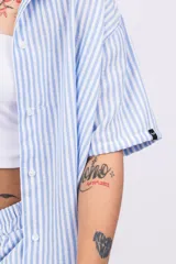 Camisa celeste a rayas verticales blancas, de lino y corte holgado.