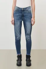 Pantalón jean de tiro medio, corte slim, color azul claro, con rotura en la rodilla y terminación desflecada.