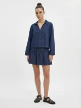 Top de manga larga en denim azul medio, con cuello camisero abierto en V y mangas amplias. Corte regular.