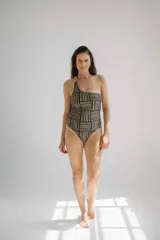 Traje de baño enterizo asimétrico con estampado de líneas horizontales negras y beige. Presenta un solo tirante ancho y espalda baja.