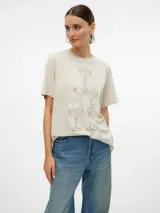 Camiseta color crema con cuello redondo y mangas cortas. Estampado frontal con copas de champagne apiladas y texto en color marrón.