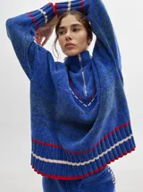Sweater azul con cuello alto con medio cierre, textura tipo terciopelo y puños acanalados.