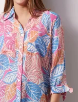 Camisa estampada con hojas en tonos celeste, naranja y verde. Tiene cuello con solapa, abertura central con botones, bolsillos aplicados en la parte delantera y mangas 3/4 con lazo.