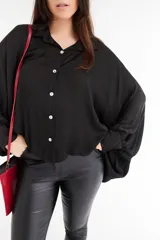 Camisa color beige de satén con corte holgado, cuello camisero y mangas largas con puños abotonados.