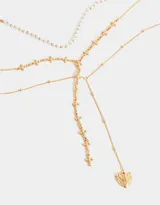 Set de tres collares dorados de diferentes largos. Uno con perlas sintéticas, otro con cruces de metal y el tercero con dije de corazón con alas.
