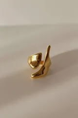 Anillo dorado de acero quirúrgico hipoalergénico, abierto y ajustable entre 16 mm y 19 mm, con diseño asimétrico y forma orgánica.