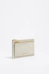 Cartera tipo sobre de nylon color gris claro, con doble compartimento con cierre de cremallera dorada. Incluye asa de mano de tejido, logo metálico de la marca y tarjetero interior.