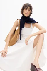 Vestido midi color blanco con finas rayas verticales en color gris, de escote cuadrado y tirantes anchos. Detalle de pliegue en delantero y cierre lateral con cremallera oculta.