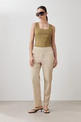 Pantalón de vestir color beige, de corte recto, con bolsillos laterales y traseros. Se ajusta a la cintura con cinturón de cuero marrón.