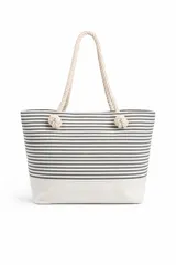 Bolso de tela tipo tote bag con estampado de rayas horizontales azules y blancas, y base de color beige. Tiene asas de cuerda de color beige.