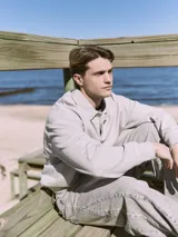 Polo de manga larga gris claro con cuello tipo camisa y cierre parcial con botones. Corte holgado y puños de canalé.