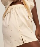 Conjunto de pijama compuesto por un top de satén color crema con lunares marrones, breteles finos regulables y escote en V con encaje, y un short con cintura elástica y estampado de lunares a juego.