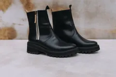 Botas de cuero color chocolate con cierre lateral metálico y suela de goma tipo track. Cuentan con tiradores en la parte superior de la caña para facilitar el calce y un diseño robusto ideal para diversas condiciones climáticas.