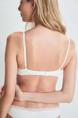Conjunto de lencería blanco con detalles de encaje, compuesto por un corpiño con aro y una bombacha tipo bikini.