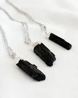 Collar con dije de turmalina negra irregular con engarce plateado y cadena de eslabones plateada.