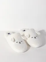 Pantufla blanca de textura peludita, con talón descubierto y diseño bordado en forma de animal, acolchada y con suela de 1,5 cm.