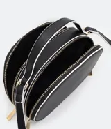 Bolso pequeño cruzado de forma redondeada, color negro con detalles en blanco. Tiene correa ajustable, tirante de mano y cierre de cremallera.