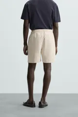 Bermuda de algodón color marrón oscuro, de corte regular fit, con cintura elástica ajustable mediante cordón. Presenta bolsillos laterales y un bolsillo trasero de vivo.