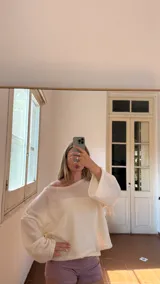 Blusa de tejido de punto color blanco, con escote barco que permite usarla caída sobre un hombro.