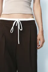 Pantalón ancho gris con textura de espiga, tiro alto, doble cintura elástica ajustable con cordón, pinzas frontales, bolsillos delanteros y falso bolsillo de vivo en la espalda.