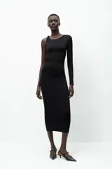 Vestido midi negro de punto, con cuello asimétrico, manga sisa, aplique metálico dorado en el hombro y drapeado lateral.