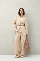 Sweater color beige de tejido de punto, con cuello redondo y mangas largas acampanadas con botones decorativos en los laterales.