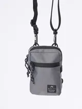 Bandolera gris con diseño compacto, cierre y correa ajustable, ideal para uso diario.