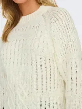 Sweater de punto color crema con diseño de trenzas y punto arroz. Tiene cuello redondo y mangas largas con puños y bajo acanalados con borde negro.