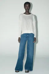 Sweater de punto calado color blanco, de corte holgado, cuello redondo y manga larga.