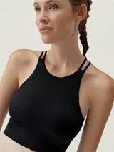 Top deportivo negro con diseño halter, tirantes finos cruzados y tejido específico para un ajuste cómodo.
