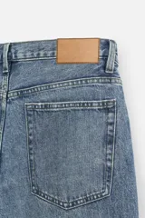Pantalón de jean gris de corte recto, con cinco bolsillos, efecto lavado y cierre frontal con botones.