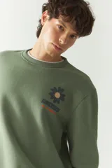 Buzo de felpa color gris claro con cuello redondo y puños y cintura acanalados. Estampado en la espalda con motivos de la naturaleza en tonos azul, verde y negro.