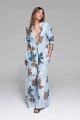 Conjunto de dos piezas compuesto por un blazer de manga larga y un pantalón palazzo de pierna ancha. Ambas prendas son de tela liviana y presentan un estampado floral en tonos celestes, azules y marrones sobre fondo celeste claro. El blazer tiene solapas y bolsillos frontales.