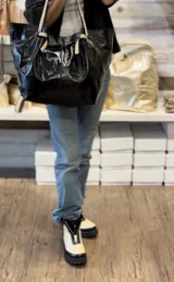 Bolso de cuero en tono marrón con asas largas y diseño espacioso.
