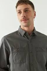 Camisa de gabardina gris con corte slim, mangas largas, cartera abotonada y dos bolsillos con solapa en el pecho.