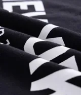 Musculosa negra de algodón con corte recto y hombros ligeramente ampliados (boxy fit). Presenta estampado frontal en blanco con el texto "URBAN SCENE TRENDS", "NEW YORK" y "Manhattan 1974".