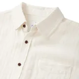 Camisa de manga corta color blanco, con cuello clásico y bolsillo en el pecho. Cierre frontal con botones marrones.