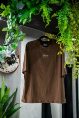 Remera oversize marrón de algodón elastizado con estampado en la espalda que incluye el texto "Crazy Hermod movement" y un diseño de zapatilla alada.