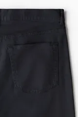 Pantalón de corte slim fit color negro, confeccionado en sarga de algodón, con cinco bolsillos, cierre con cremallera y botón.