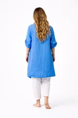 Campera larga tipo sobrecamisa o saco ligero de lino, color azul vibrante. Presenta cuello solapa, mangas largas enrolladas con presilla y bolsillos frontales. El ruedo es asimétrico con terminaciones de cordones.