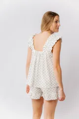 Pijama de algodón estampado con pequeñas flores en tonos pastel. Incluye una musculosa con escote recto, frunces y breteles, y un short con elástico en la cintura y terminación con volado.