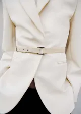 Blazer color crema con solapas de muesca, hombros estructurados, bolsillos de ribete, cinturón desmontable y forro interior.