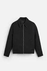 Sobrecamisa negra de tejido con textura, corte recto, cuello solapa, cierre frontal con cremallera, bolsillos laterales y puños abotonados.