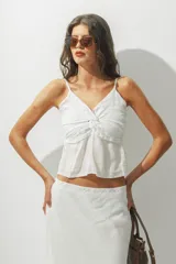 Top blanco con breteles finos y detalle de nudo en el centro del busto.