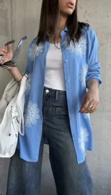 Camisa celeste de manga larga con bordados de flores blancas.