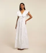Vestido midi evasé sin mangas confeccionado en tricolina blanca con escote en V, espalda descotada, volados en los hombros, cintura elástica y lazos en la cintura, además de agujeros en el tejido.