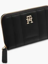 Billetera Tommy Hilfiger negra con diseño acolchado, cierre de cremallera, múltiples ranuras interiores para tarjetas, compartimento interior para billetes, bolsillo interior con cierre de solapa e insignia del monograma TH dorada en la parte delantera.
