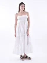 Vestido largo blanco de verano con tirantes finos ajustables y corpiño fruncido (smock). La falda es de corte amplio con volados en capas.