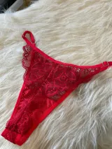 Conjunto de lencería rojo de encaje, compuesto por un bralette triangular con breteles regulables y una tanga regulable con corte media less y entrepierna de algodón.