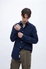 Camisa celeste de algodón, corte regular fit, con cuello solapa clásico, manga larga, bolsillo en el pecho y botones personalizados.